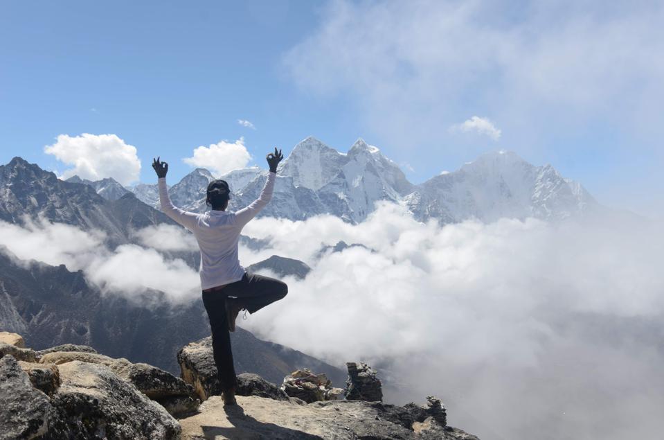 Amiti doing yoga on the top of a mountain.